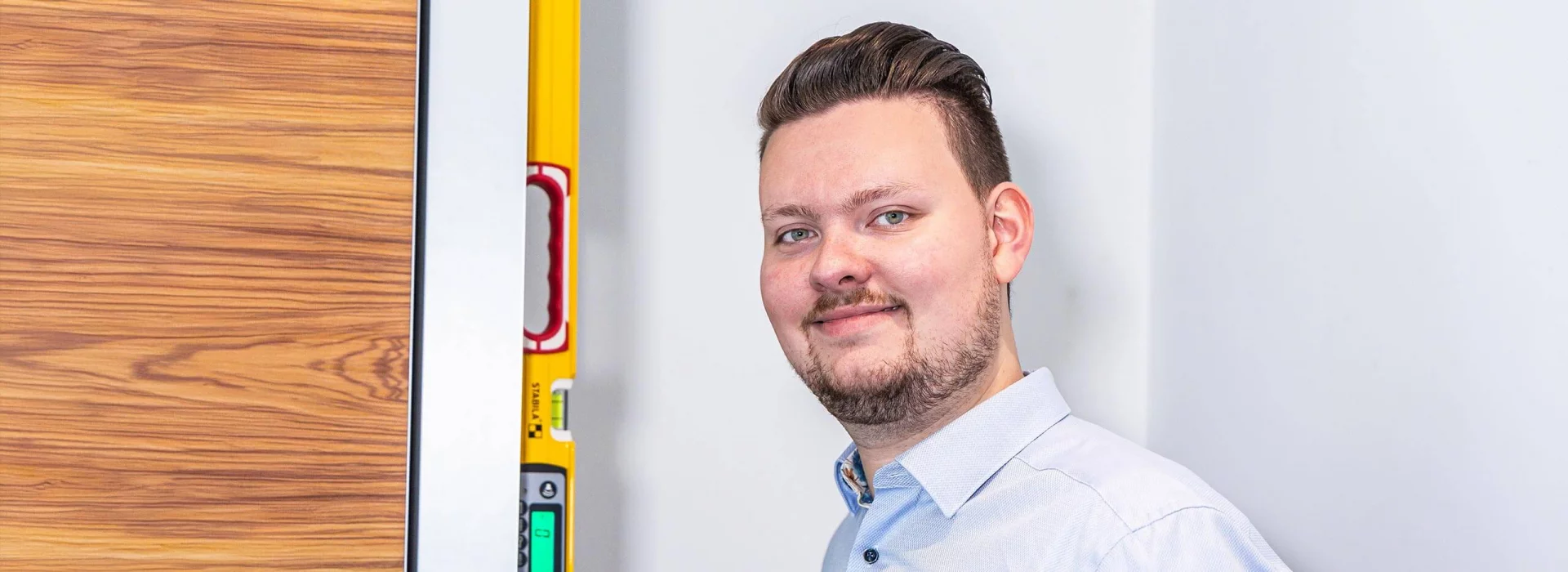 Gero Keuthen mit einer Wasserwaage, die er an einen Schrank hält.